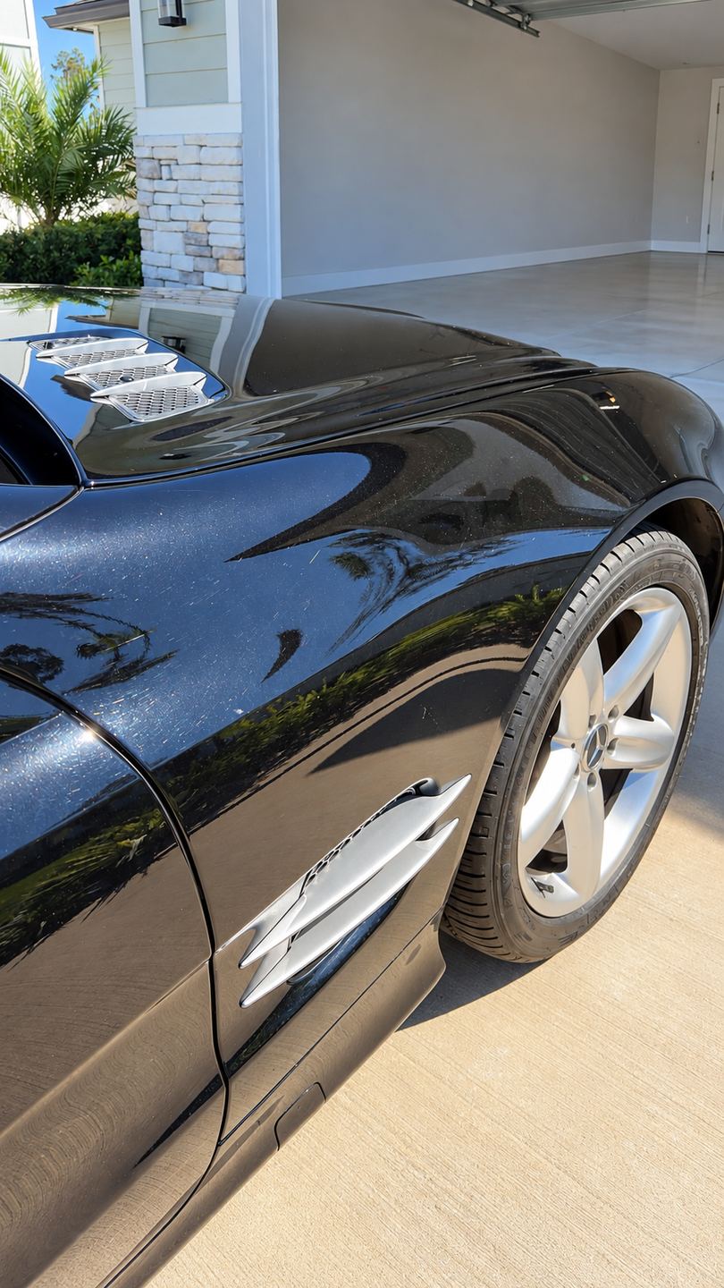 Black car fender before detailing, dull with visible swirl marks